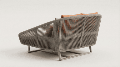 A contemporary daybed constructed with a woven rope frame and a metal base. It features a plush, light-colored cushion and several decorative pillows in coral and beige tones. The design suggests suitability for outdoor or modern indoor use. — 3D model