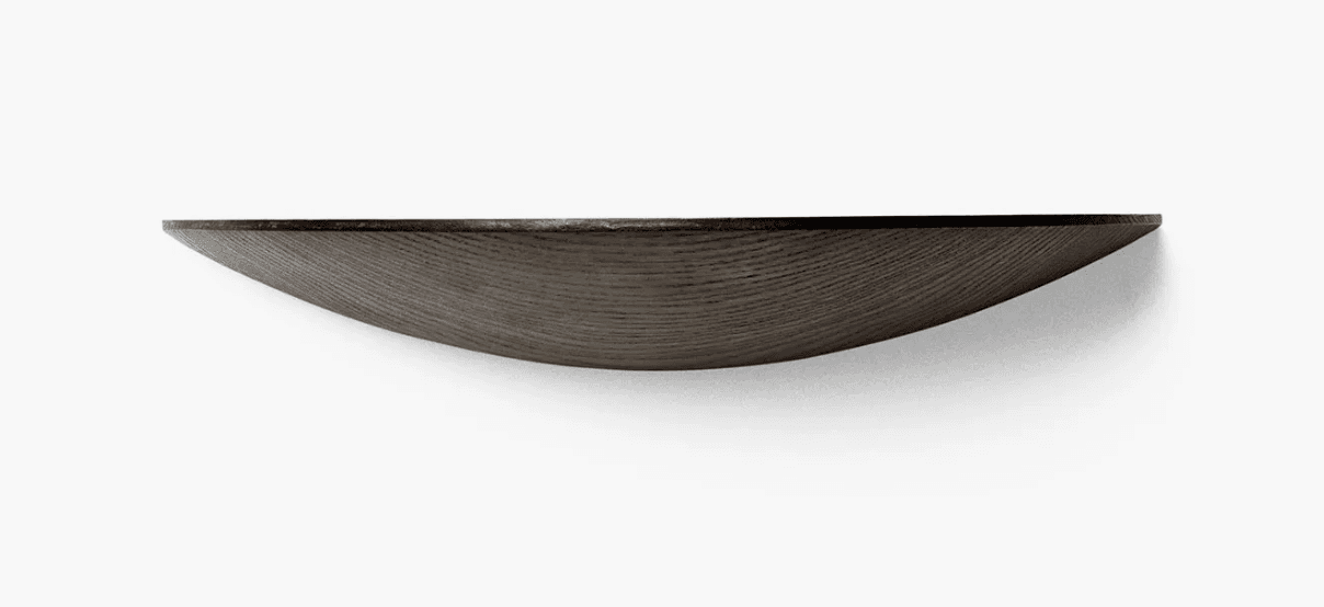 A dark-stained wood floating wall shelf featuring a distinctive concave or bowl-like profile. The visible wood grain suggests a natural material, possibly oak or ash, finished in a deep, muted brown or charcoal tone. It is designed to appear as if it's emerging from the wall, without visible support brackets. — 3D model