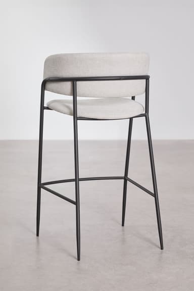 A modern bar stool featuring a light gray upholstered seat and a wraparound backrest that seamlessly integrates armrests. The seat and back are cushioned, providing comfort. The entire upholstered section is supported by a slender black metal frame which forms the four legs, reinforced by a circular footrest at the bottom. The design is minimalist and contemporary. — 3D model