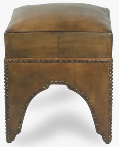 A square-shaped ottoman with a cushioned top, upholstered in what appears to be aged or distressed leather. The base is adorned with decorative brass or bronze nailhead trim. The sides of the base feature an arched cutout. — 3D model