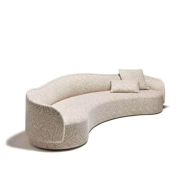 A contemporary curved sofa, fully upholstered in a light-colored patterned fabric, featuring a continuous backrest and armrests, and accompanied by two matching throw pillows. — 3D model