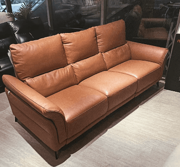 A modern three-seater sofa upholstered in tan leather, featuring segmented back cushions, individual seat cushions, and gently rolled arms. It stands on slender, angled black metal legs. — 3D model