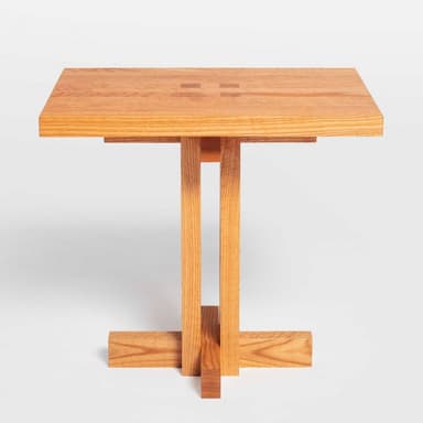 A square wooden pedestal table with a natural oak finish and a subtle geometric inlay on the tabletop, supported by a central column and cross-shaped base. — 3D model