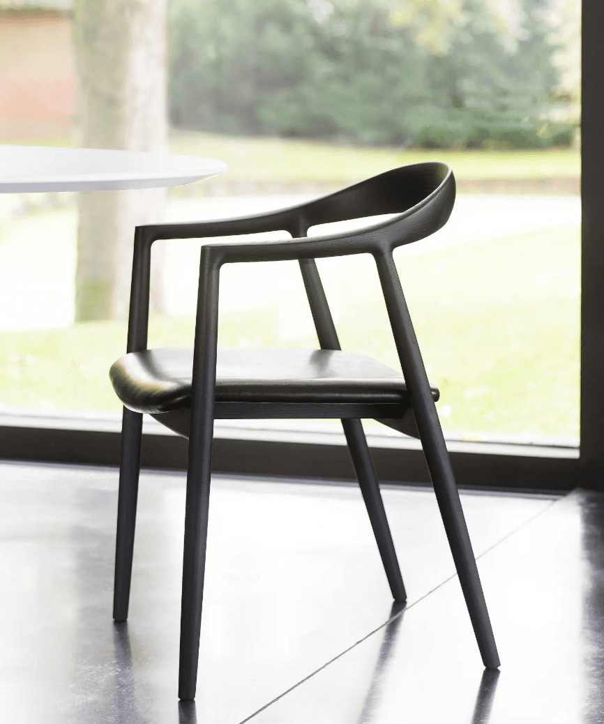 A contemporary black armchair featuring a molded frame with integrated armrests and a curved backrest, complemented by a padded, upholstered seat. — 3D model
