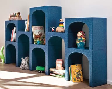 A contemporary modular shelving unit composed of three connected, stepped sections. Each section consists of stacked blocks featuring distinct arched openings, creating a series of display shelves. The unit is rendered in a uniform dark blue color with a textured, granular finish, resembling a composite or stone-like material. The design is geometric and architectural, with a stepped profile ascending from left to right. — 3D model