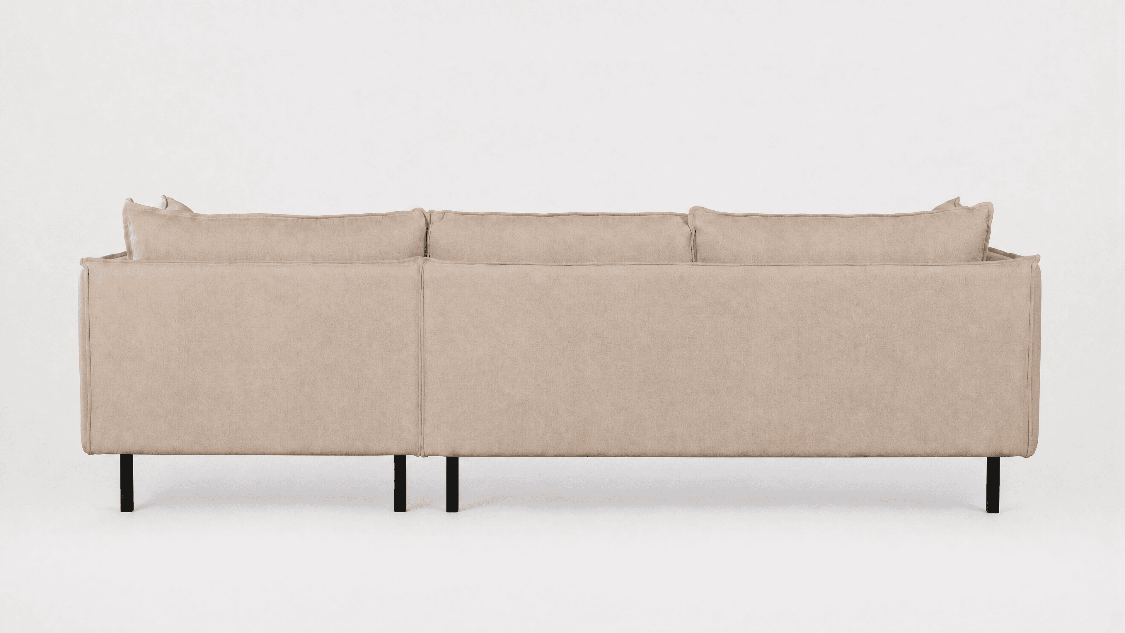 A contemporary sectional sofa, seen from the rear and side, upholstered in light beige/greige fabric with black metal legs. It features multiple loose back cushions and a low-profile design. — 3D model