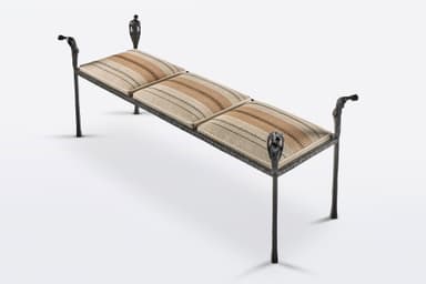 A distinctive figural wrought iron bench featuring a dark, textured metal frame with decorative uprights sculpted as human figures, supporting segmented upholstered cushions with a striped pattern. The bench has four slender legs and decorative arm-like elements at each end, also featuring figural motifs. — 3D model