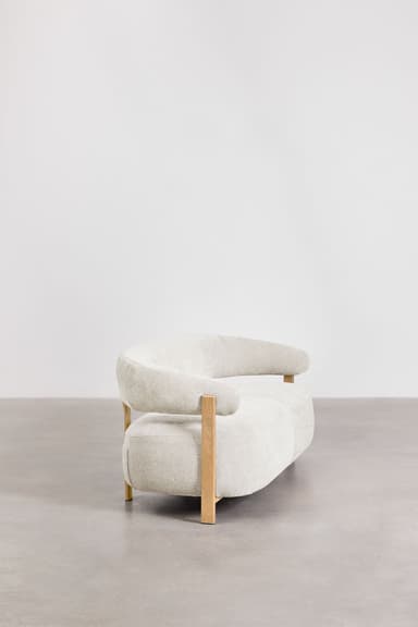 A contemporary sofa with a curved, organic shape. It features a thick, upholstered seat and backrest with rounded edges. The frame is partially exposed, with light-colored wooden legs and armrest supports that extend upward. The upholstery appears to be a textured fabric. — 3D model