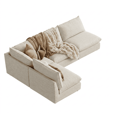 An L-shaped modular sectional sofa upholstered in a light beige, textured fabric, featuring plush, loose seat and back cushions. The sofa includes two throw pillows and two blankets in complementary brown and cream tones, suggesting a focus on comfort and a relaxed, contemporary aesthetic. — 3D model