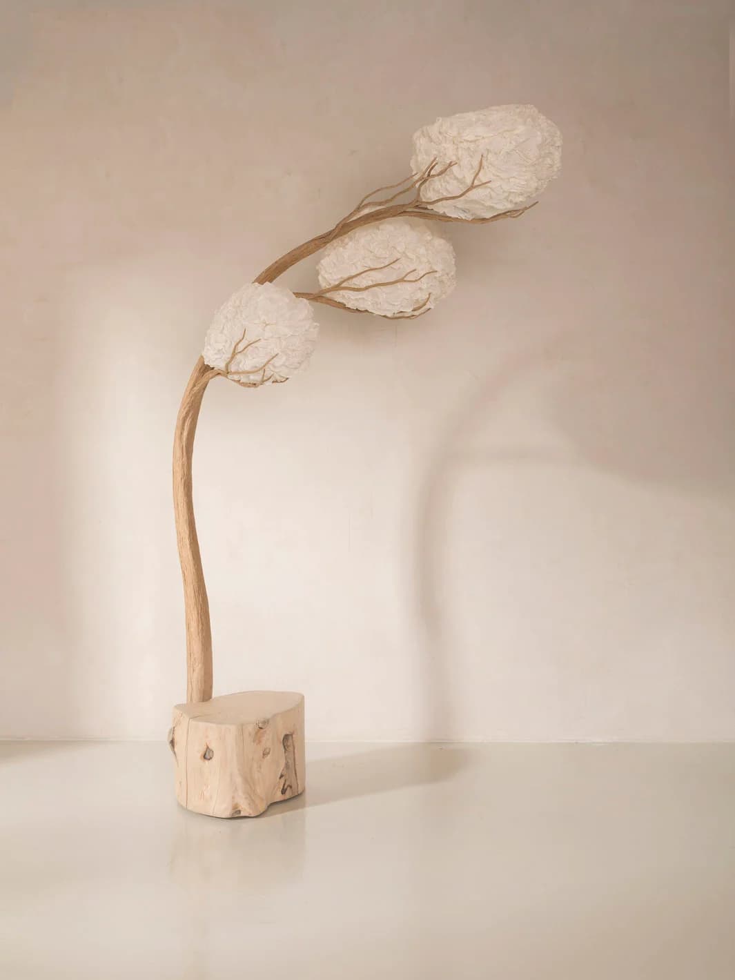 An artistic floor lamp featuring a natural wood block base, a gracefully curving branch-like stem, and three spherical, crinkled white paper or fabric shades designed to resemble blossoms or clouds. — 3D model