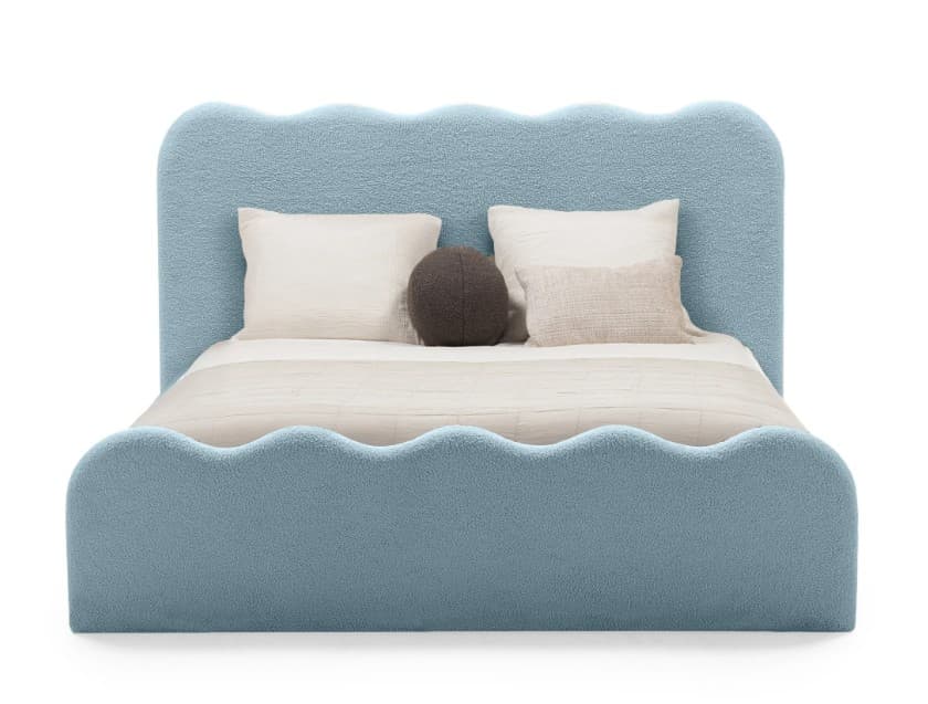 A child's bed with a playful, wavy design. The headboard and footboard feature undulating curves, resembling soft waves. The upholstery has a textured, plush appearance, similar to sheepskin or bouclé fabric. The bed is presented with bedding, including two rectangular pillows and one round bolster pillow. The color is a light, pastel blue. — 3D model