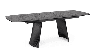 A contemporary dining table with a textured, dark surface and a black, ribbed pedestal base. The tabletop appears to be segmented and has a slightly irregular, wave-like texture. The base consists of two flared, curved legs with a ribbed pattern running vertically. — 3D model