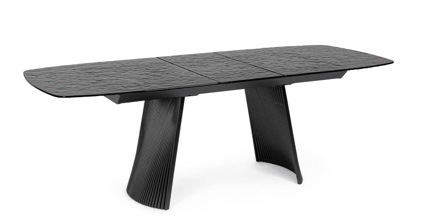 A contemporary dining table with a textured, dark surface and a black, ribbed pedestal base. The tabletop appears to be segmented and has a slightly irregular, wave-like texture. The base consists of two flared, curved legs with a ribbed pattern running vertically. — 3D model