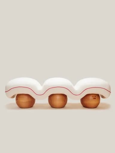 A contemporary bench with a wavy, bulbous white upholstered seat. The seat is supported by three spherical wooden legs with a natural finish. A thin red line accents the underside of the upholstered seat, following its undulating form. — 3D model