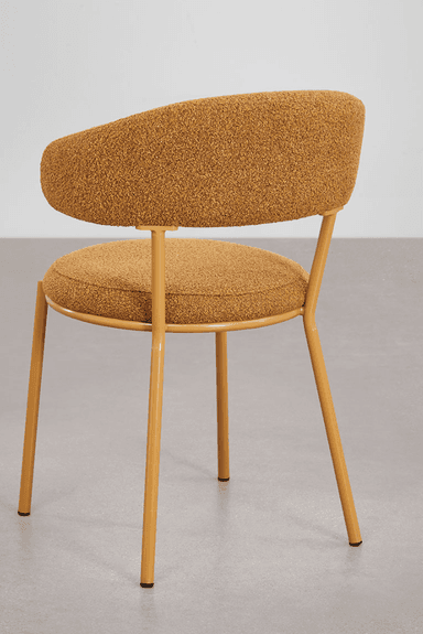 A modern accent chair with a rounded backrest that extends into armrests. The seat and backrest are upholstered in a textured, boucle-like fabric. The chair is supported by four slender, tapered metal legs finished in a mustard yellow color. — 3D model