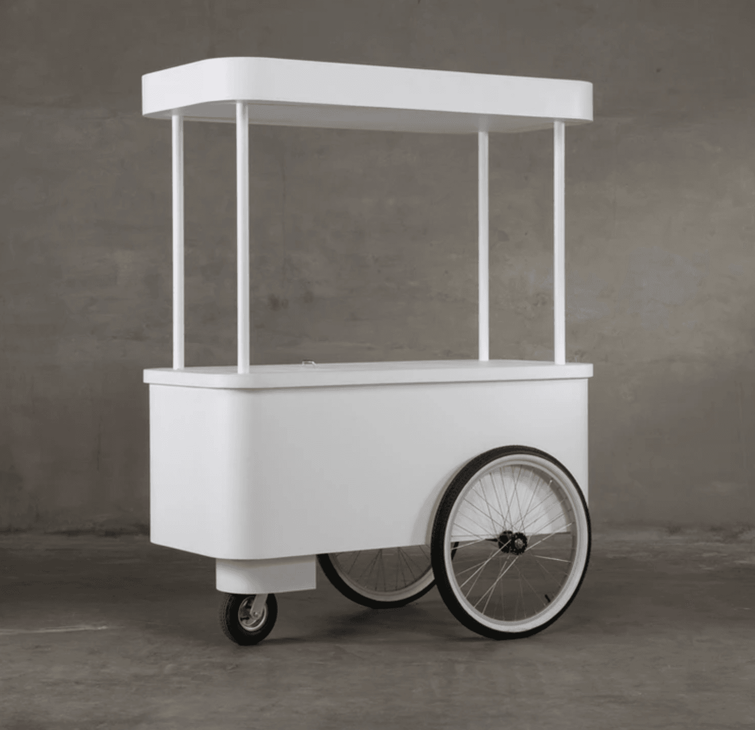 A mobile white cart with a canopy supported by vertical posts. The cart has a rectangular body with rounded corners and is equipped with two large spoked wheels at the rear and a smaller swivel wheel at the front for mobility. The top surface of the cart's body is flat, and a slightly raised canopy structure is positioned above it. — 3D model