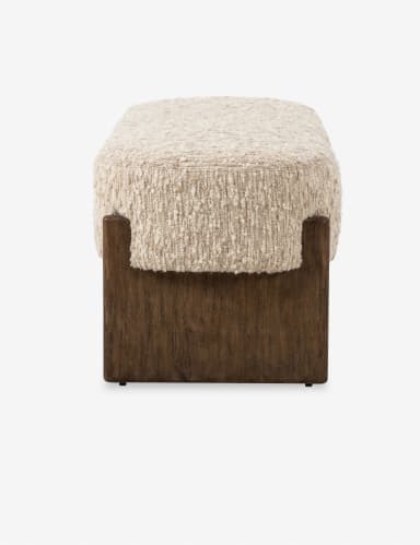 A long, upholstered bench with a textured, boucle-like fabric in a neutral off-white color. The bench features a solid, dark wood frame with a minimalist design. The frame consists of two horizontal pieces connecting the legs, which have a subtle, angled profile. — 3D model