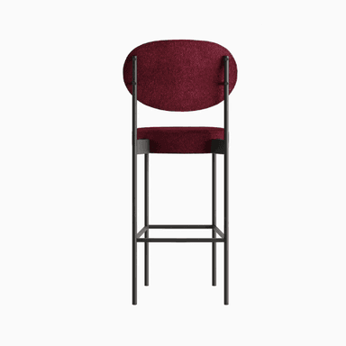 A modern bar stool with a minimalist design. It features a slender metal frame supporting a circular seat and an oval backrest, both upholstered in a textured, deep red fabric. The frame has a dark, matte finish, and the legs are connected by horizontal supports for stability. — 3D model