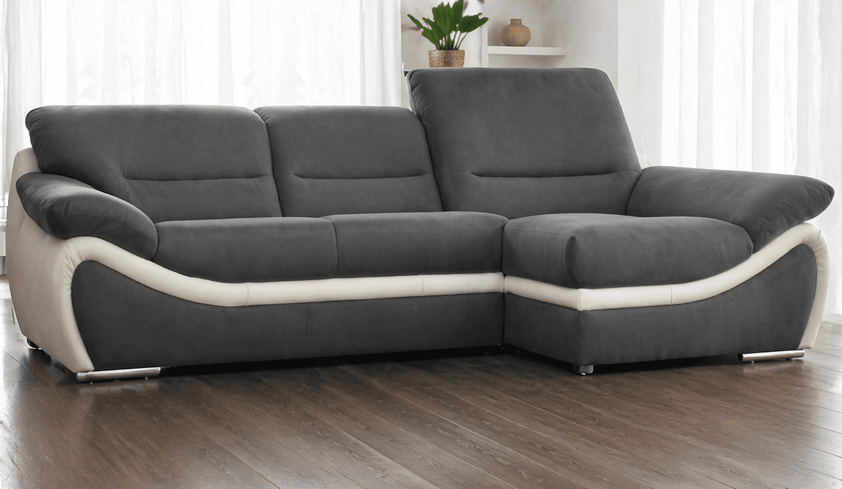 A modern sectional sofa with a chaise lounge component. The sofa features multiple seat cushions and backrests, with an adjustable headrest on one side. The design incorporates a two-tone color scheme, with dark gray upholstery for the seating areas and backrests, and a lighter cream or off-white material for the lower frame and armrest accents. The sofa is raised on small, low-profile feet. — 3D model