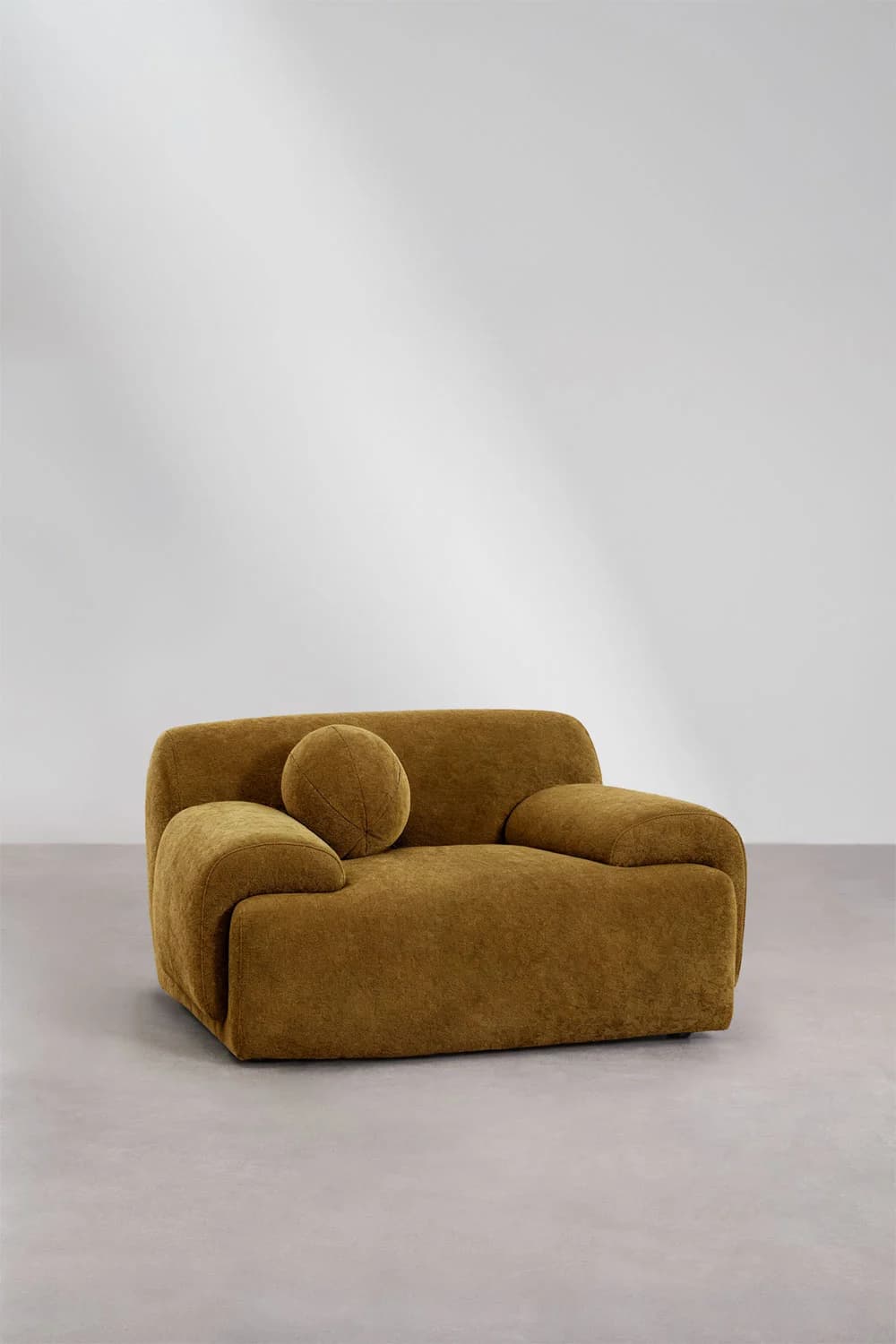 A low-profile, plush armchair with rounded edges and a textured fabric upholstery. It features a singular, spherical throw pillow placed against the backrest. The armchair has wide, integrated armrests that form a continuous line with the seat and back. — 3D model