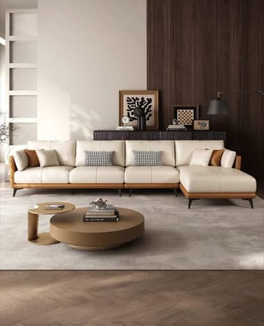 A modern sectional sofa featuring a chaise lounge. The main body of the sofa is upholstered in a light cream or off-white material, likely leather or a high-quality fabric. The arms and the side of the chaise are upholstered in a contrasting warm brown material, possibly leather, with a visible wood grain texture on the frame. It is supported by thin, black, angled legs. The sofa includes multiple throw pillows; two with a black and white geometric pattern and two solid colored pillows in cream and brown. — 3D model