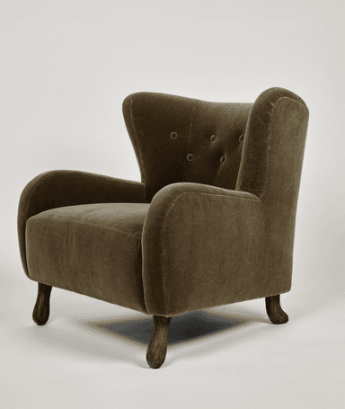 An upholstered wingback armchair featuring a high backrest with button tufting, gently rolled arms, and short, turned wooden legs. The chair is covered in a plush, textured fabric, possibly velvet or chenille, in an olive green hue. The overall design suggests a traditional or classic aesthetic. — 3D model