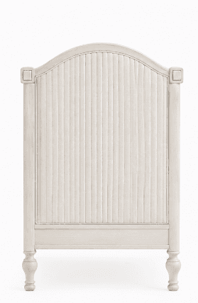 A light-colored, traditional style wooden crib featuring turned spindles and paneled end posts. The finish appears distressed or washed, giving it a soft, aged aesthetic. A white mattress is visible inside. — 3D model