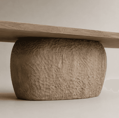 A substantial dining table featuring a light-toned, rectangular solid wood slab top with softly tapered edges, supported by a single, dark-toned, heavily sculpted and textured pedestal base with an organic, irregular form. — 3D model