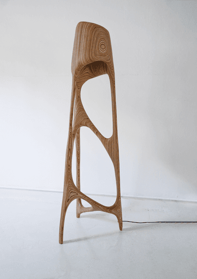 A contemporary bar stool with an organic, sculpted form. The stool features a high back and appears to be constructed from layered bentwood or plywood, showcasing a distinctive wood grain pattern. Its structure is characterized by flowing lines and open negative spaces, creating a visually dynamic and lightweight appearance. The stool has four legs that taper towards the floor. — 3D model
