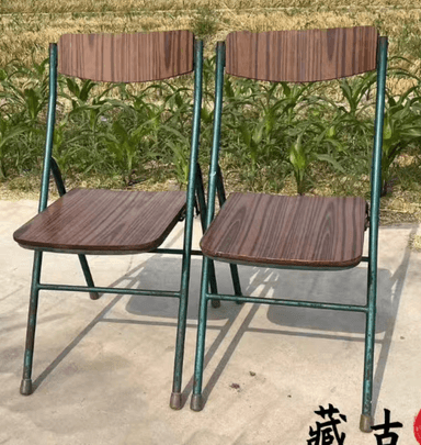 A folding chair with a dark green metal frame and a contoured seat and backrest featuring a dark wood grain finish. — 3D model