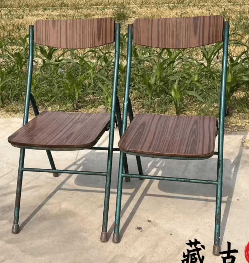 A folding chair with a dark green metal frame and a contoured seat and backrest featuring a dark wood grain finish. — 3D model