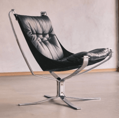 A modern lounge chair with a cantilevered, upholstered seat and back supported by a polished metal frame. The seat and back appear to be made of tufted black leather, suspended within a black fabric sling. The base is a four-pointed star shape, also constructed from polished metal, providing a stable foundation. The design features clean lines and a sleek aesthetic, typical of mid-century modern or contemporary design. — 3D model