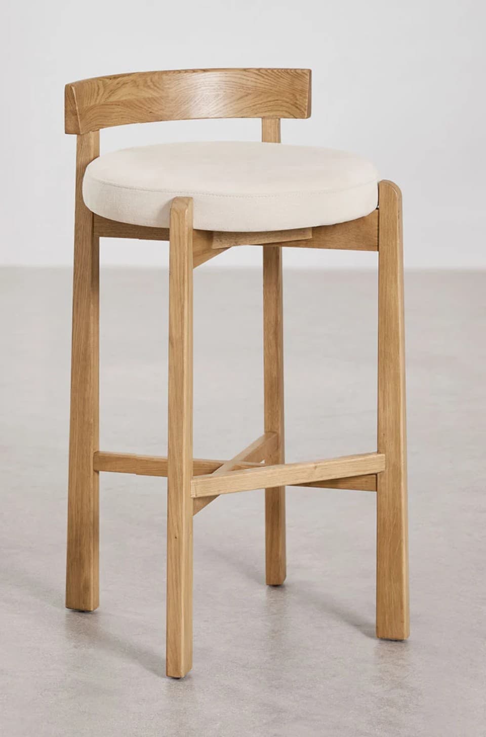 A wooden bar stool with a cushioned seat and a curved backrest. The stool has four legs connected by crossbars for stability. The seat is round and upholstered in a light-colored fabric, and the backrest is a gently curved wooden piece attached to the upper part of the rear legs. — 3D model