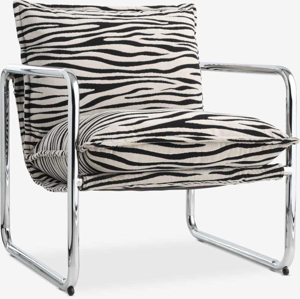 A modern lounge chair featuring a polished chrome tubular steel frame and bold zebra print fabric cushions. The design is reminiscent of the Bauhaus era, with a minimalist aesthetic and industrial materials. The chair has a seat cushion, back cushion, and armrests that are part of the continuous tubular frame. — 3D model