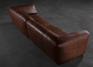 A contemporary two-seater sofa upholstered in brown leather. The sofa features a low profile with generously padded cushions for both the seat and back. Its arms are softly rounded and extend slightly outward from the main body. The overall design emphasizes comfort and a modern aesthetic, with a visible seam line dividing the two seat cushions. — 3D model