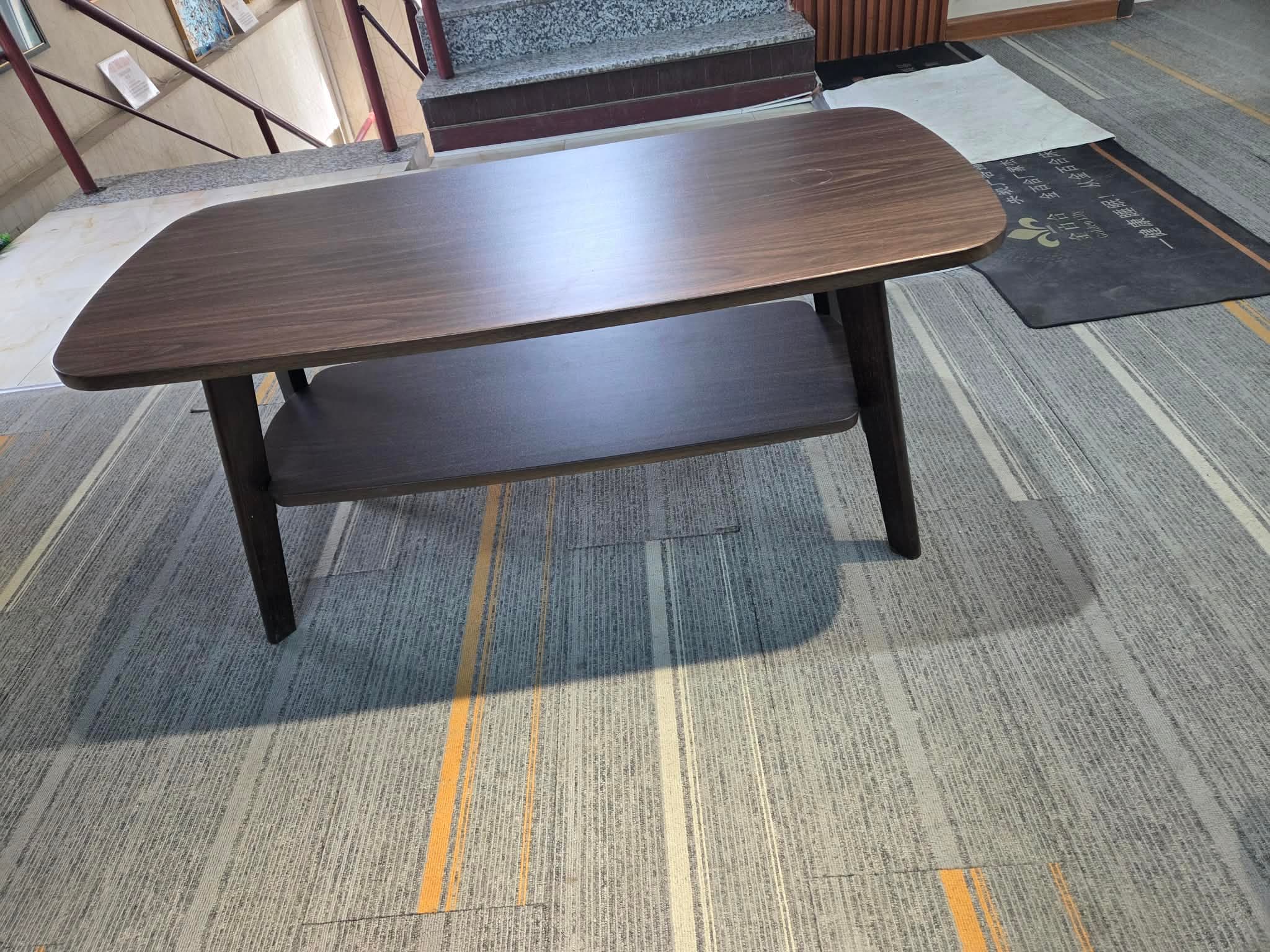 A dark brown rectangular coffee table featuring softly rounded corners, a lower storage shelf, and four outward-tapering legs. — 3D model