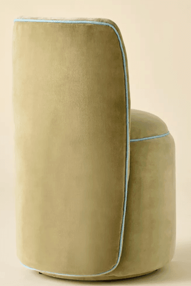 A fully upholstered accent chair featuring a low, curved backrest and a circular seat, both resting on a seamless cylindrical base. The entire piece is covered in a plush pistachio green velvet, accented by thin light blue piping around the edge of the seat and along the contours of the backrest. The chair has no visible legs, contributing to its monolithic and modern appearance. — 3D model