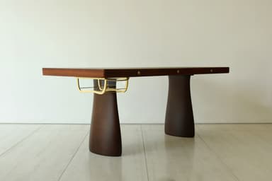 A sleek, dark brown executive desk featuring a substantial rectangular top supported by two wide, tapering sculptural pedestal bases, accented with brass details and integrated drawers. — 3D model