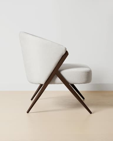 A modern armchair with a rounded back and seat, upholstered in a textured off-white fabric. The frame and legs are made of dark wood, featuring an angular, open design that supports the upholstered shell. — 3D model
