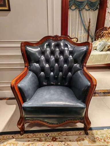 A luxurious armchair rendered in a Rococo style, featuring a dark, elaborately carved wooden frame and rich navy blue tufted leather upholstery, accented with metallic nailhead trim. — 3D model
