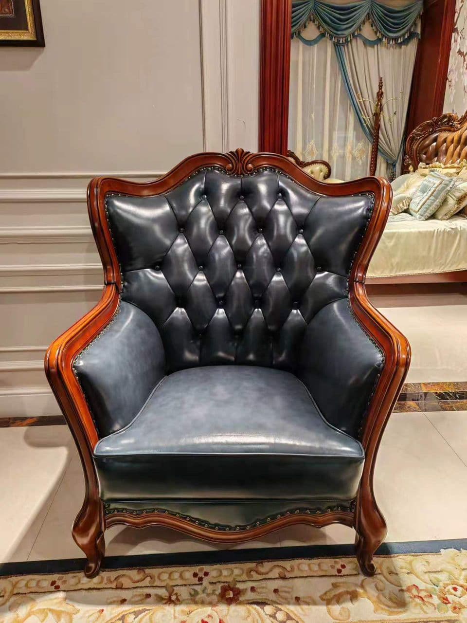 A luxurious armchair rendered in a Rococo style, featuring a dark, elaborately carved wooden frame and rich navy blue tufted leather upholstery, accented with metallic nailhead trim. — 3D model
