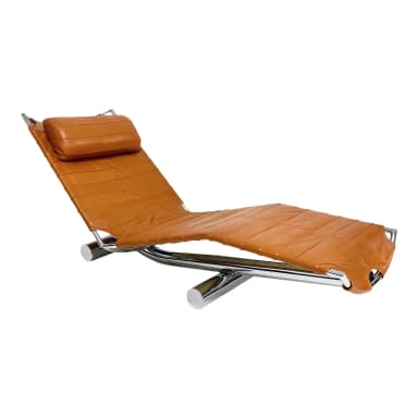 A contemporary chaise lounge with a curved, reclining design. The seat and back are upholstered in a stitched, padded orange-brown leather or leather-like material. The frame appears to be constructed from polished chrome or stainless steel, providing a sleek, modern aesthetic. A cylindrical headrest pillow, matching the upholstery, is attached to the upper section. — 3D model