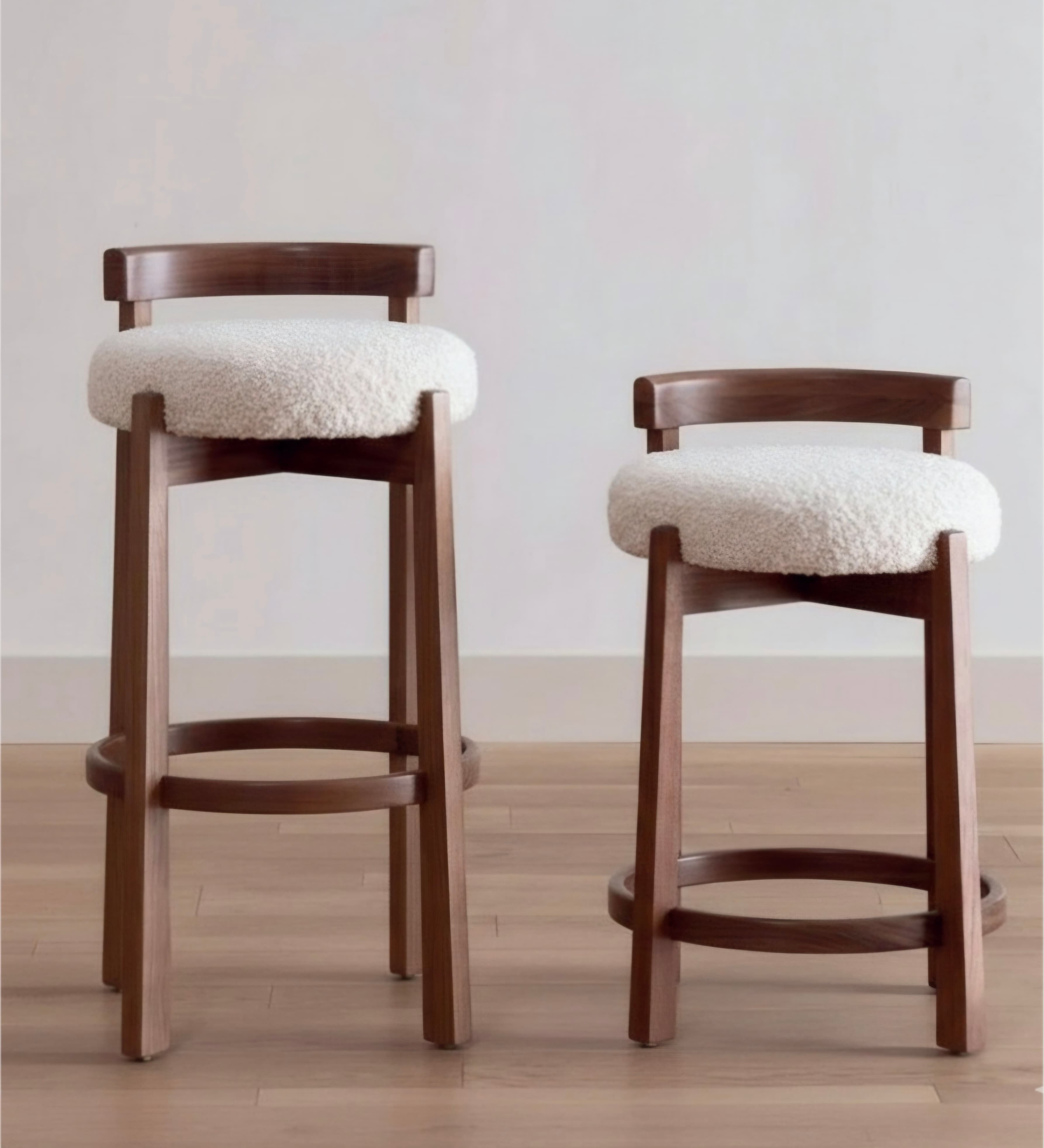 A modern bar stool featuring a dark walnut-finished wooden frame, a gently curved backrest, and a circular seat upholstered in textured cream boucle fabric. It includes a circular wooden footrest for comfort. — 3D model