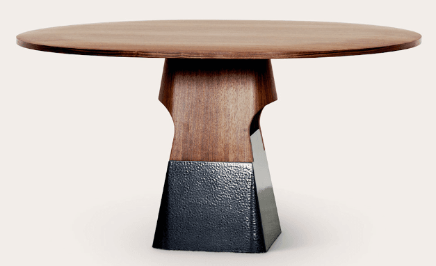 A round-topped dining table with a distinctive pedestal base. The tabletop is made of wood with a visible grain. The pedestal is composed of two sections: an upper section with a sculpted wooden form featuring cutouts, and a lower, tapered base with a textured dark finish. — 3D model