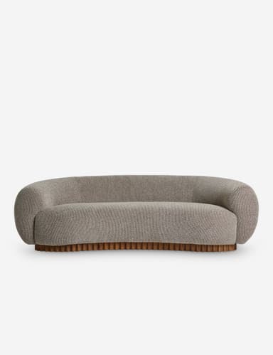 A curved sofa with a rounded silhouette, featuring a textured fabric upholstery and a distinctive wooden base with vertical fluting. The sofa has integrated armrests that flow into the backrest, creating a continuous, organic form. The base is composed of numerous closely spaced, vertical wooden elements. — 3D model