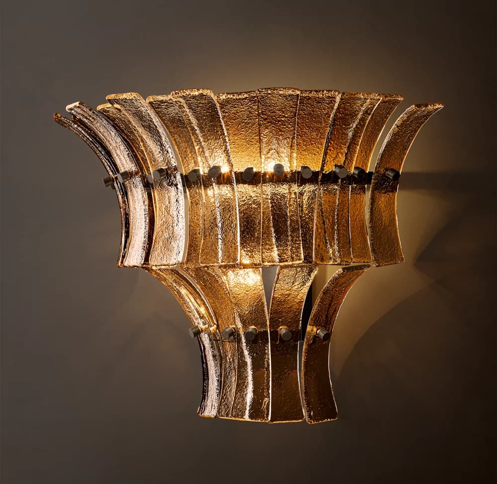 A wall-mounted lighting fixture featuring a two-tiered design composed of numerous individual textured amber/gold glass panels. These panels are arranged in a fanned, curvilinear pattern, creating an upward and downward radiating form. The panels are affixed to a dark metal frame, visible in the gaps, which also houses the light sources that illuminate the textured glass from within, producing a warm, diffused glow. — 3D model