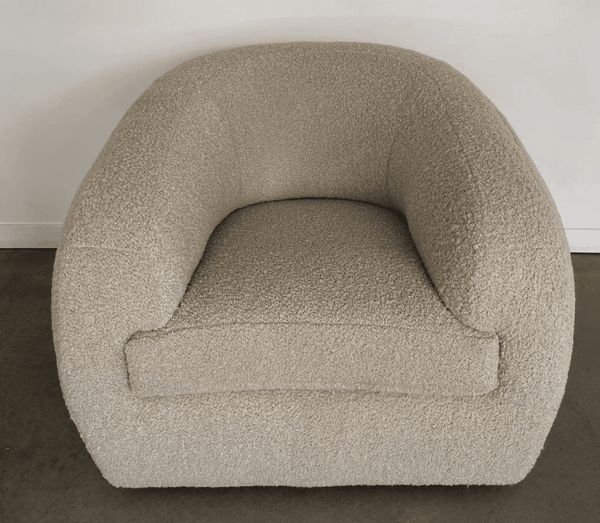 A rounded armchair with a plush, textured upholstery. The armchair features a deep seat and a wraparound backrest that seamlessly integrates into the armrests. The texture appears to be a boucle or similar looped fabric, giving it a soft and inviting appearance. — 3D model