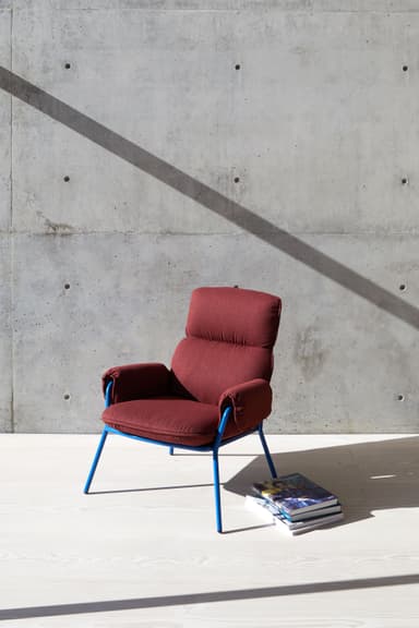 A modern armchair with a high back and padded arms, supported by a slender white metal frame. The upholstery appears to be a textured fabric in a neutral, multi-tonal beige or tan color. — 3D model
