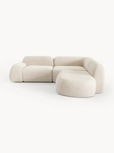 A contemporary modular sectional sofa featuring soft, rounded forms and upholstered in a light-colored, textured fabric. The configuration includes a two-seat section, a corner piece, and an integrated ottoman/chaise extension, creating an L-shaped layout with a low profile. — 3D model