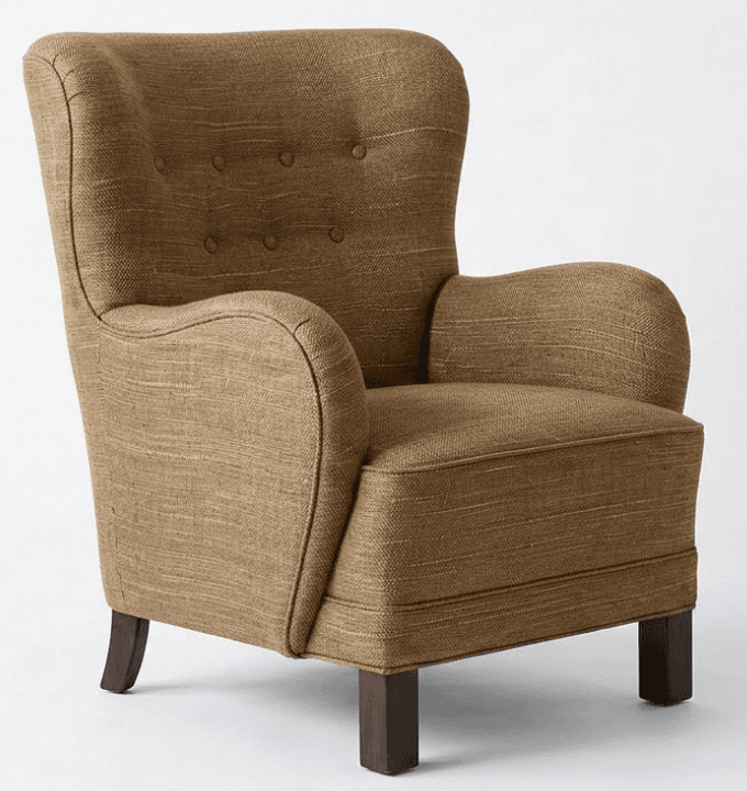 A high-backed upholstered armchair featuring a classic wingback silhouette with subtle wing elements, adorned with button tufting on the backrest. It has rounded, rolled arms and rests on short, dark-stained wooden block feet. The chair is upholstered in a textured, woven fabric in a neutral brown or tan color. — 3D model